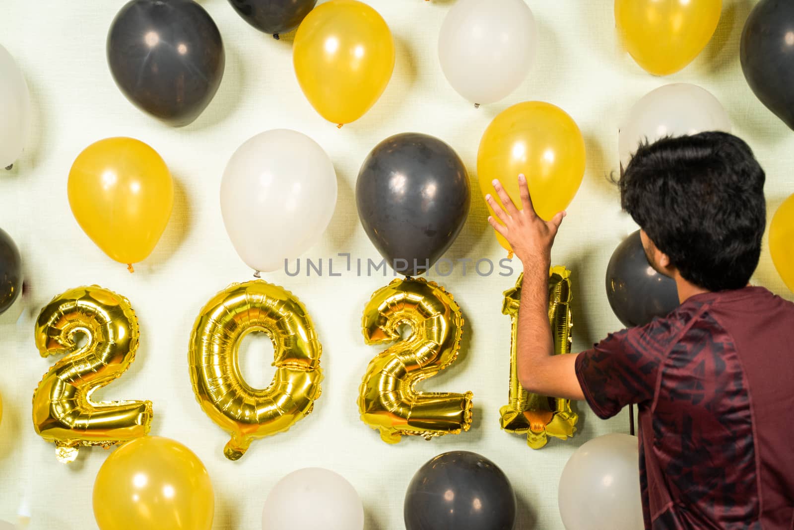 Selective Focucs on hand holding balloons, Concept of 2021 new year party decoration - Young man busy in decorating wall with balloons for new year party celebration. by lakshmiprasad.maski@gmai.com
