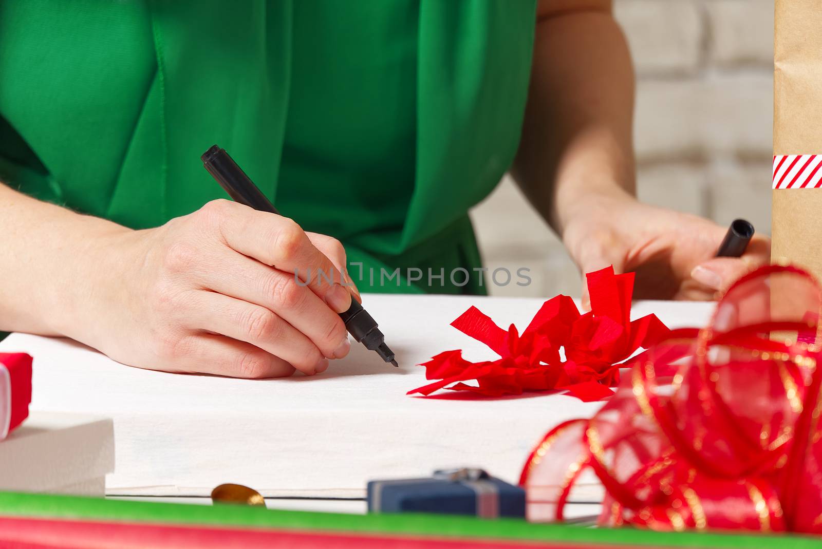 woman signs christmas gifts with a black pen. christmas gifts packing service concept