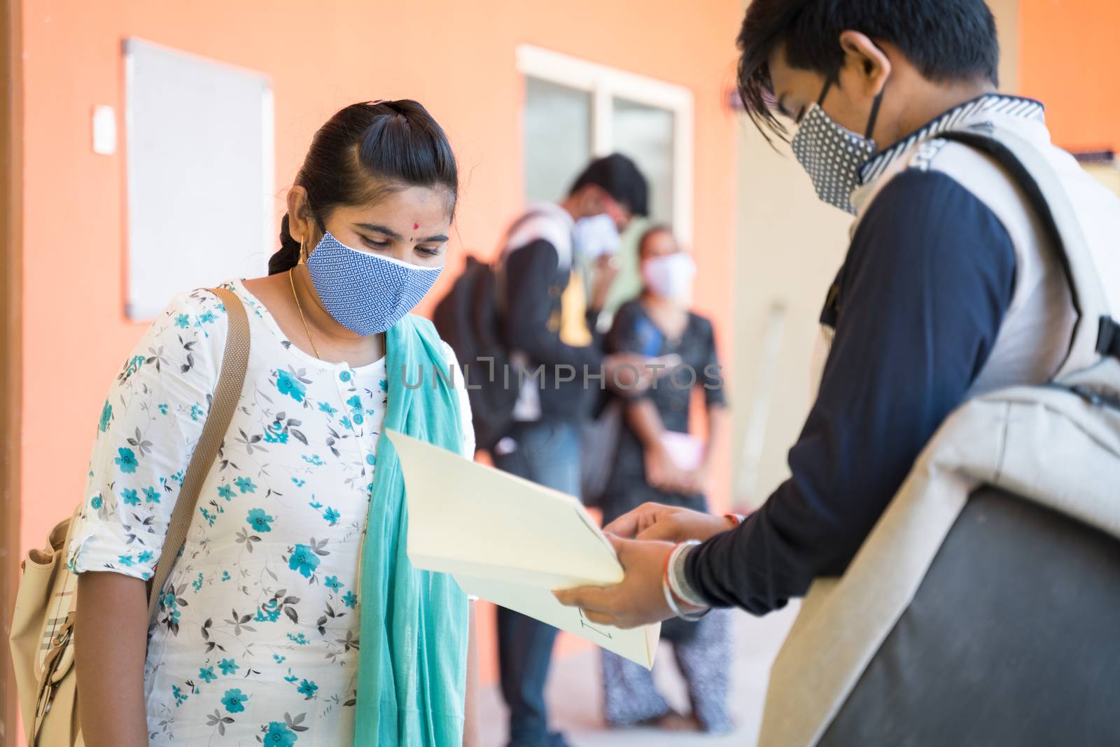 University students in medical mask discussing at college corridor - concept of college reopen after covid-19 coronavirus pandemic. by lakshmiprasad.maski@gmai.com