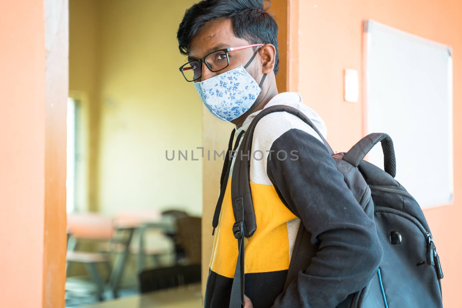 College student with face mask looking into camera before entering classroom - concept of college reopen, new normal lifestyle after coronavirus or covid-19 pandemic.