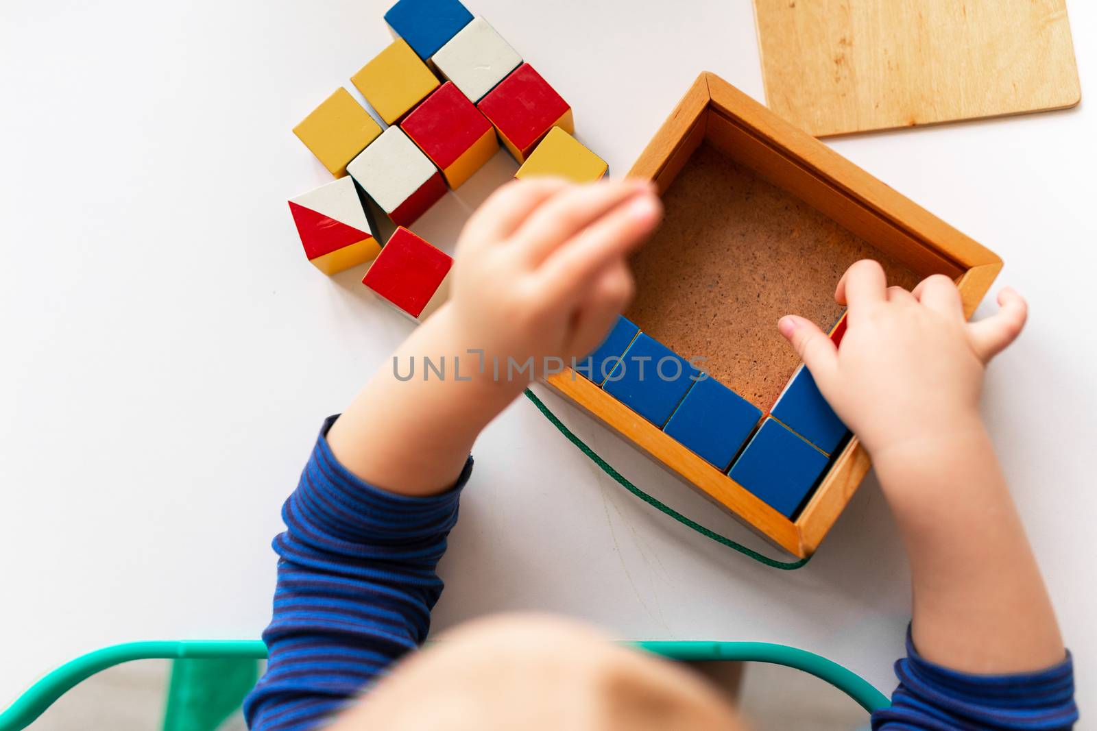 Baby playing with wooden blocks creating a pattern, focusing on hands. Nikitin unicube game