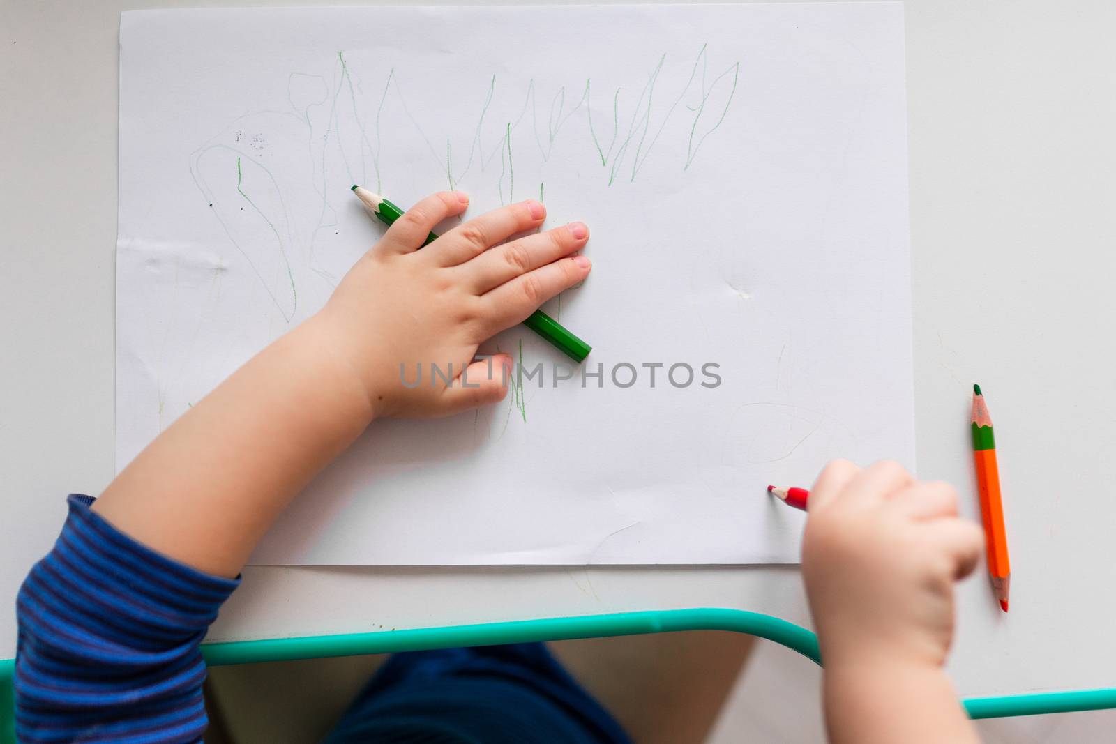 Baby boy drawing a picture with colored pencils, focus on hands