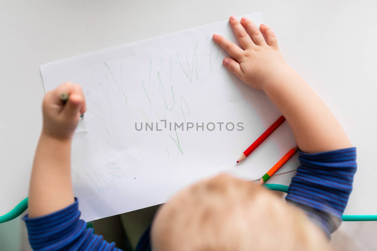 Left handed baby boy drawing a picture with colored pencils