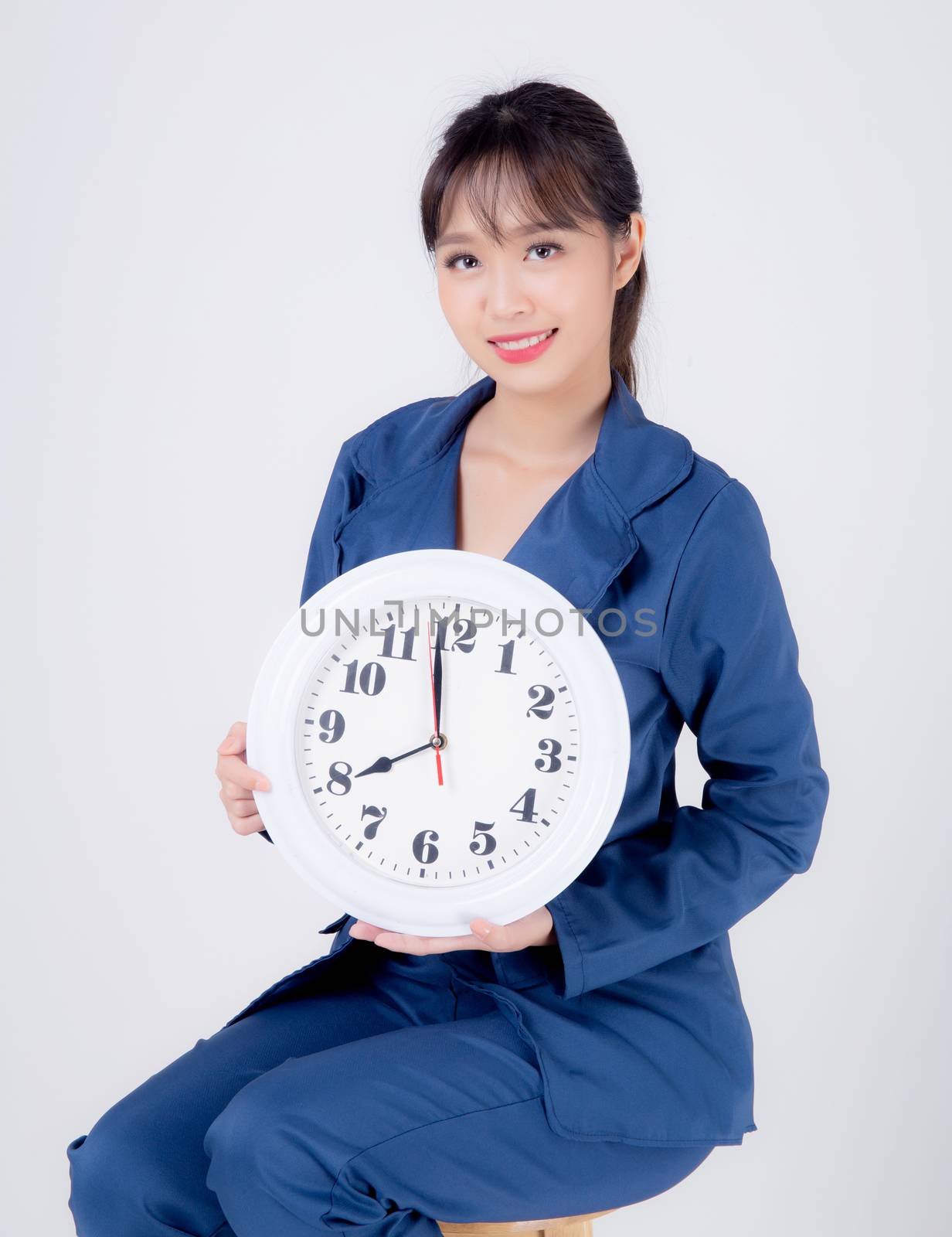 Beautiful portrait young business asian woman smiling holding clock isolated on white background, happy businesswoman schedule time of work, confident girl showing watch, management time concept.
