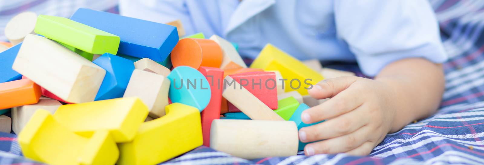 Little boy is playing for idea and inspiration with toy block in the grass field, kid learning with construction block for education, child activity and game in the park with happy, banner website.
