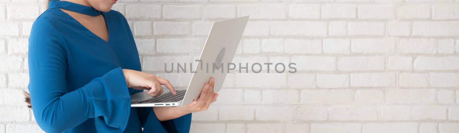 Beautiful asian young woman using laptop standing at workplace o by nnudoo