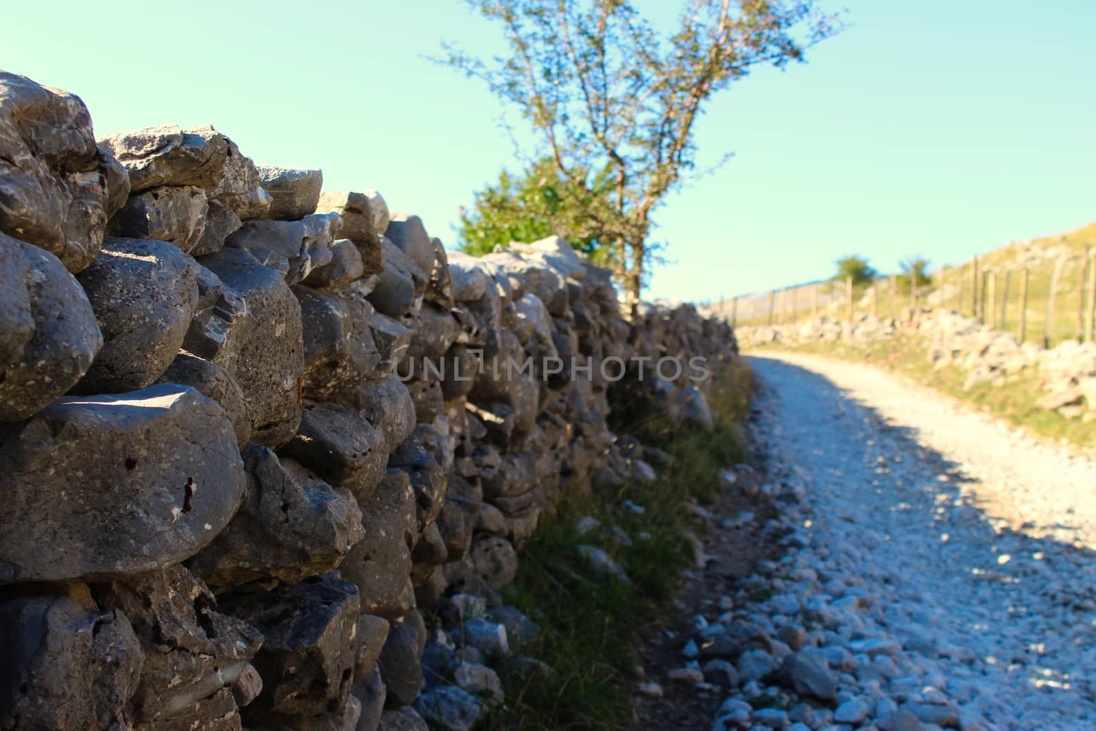 A wall of just stacked by the roadside. Stones stacked in the wall next to the road to fence the field from the road. Road to the old Bosnian village of Lukomir. by mahirrov
