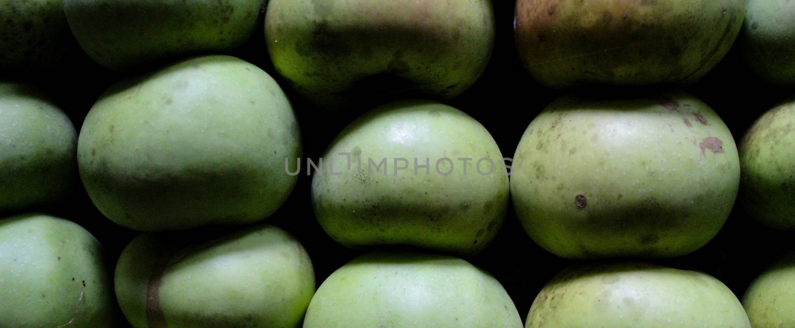 Banner of homemade apples of different sizes perfectly stacked in a crate. Apples in a crate in a storeroom in a dark room to keep them lasting longer. Variety Kanicka. Zavidovici, Bosnia and Herzegovina.