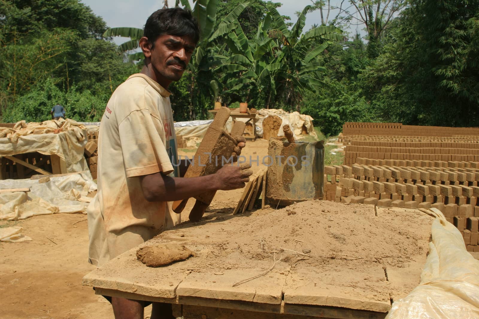 Sri Lanka 4.5.2006 worker shaping mud and clay bricks for manufacture of traditional mud bricks for building. High quality photo