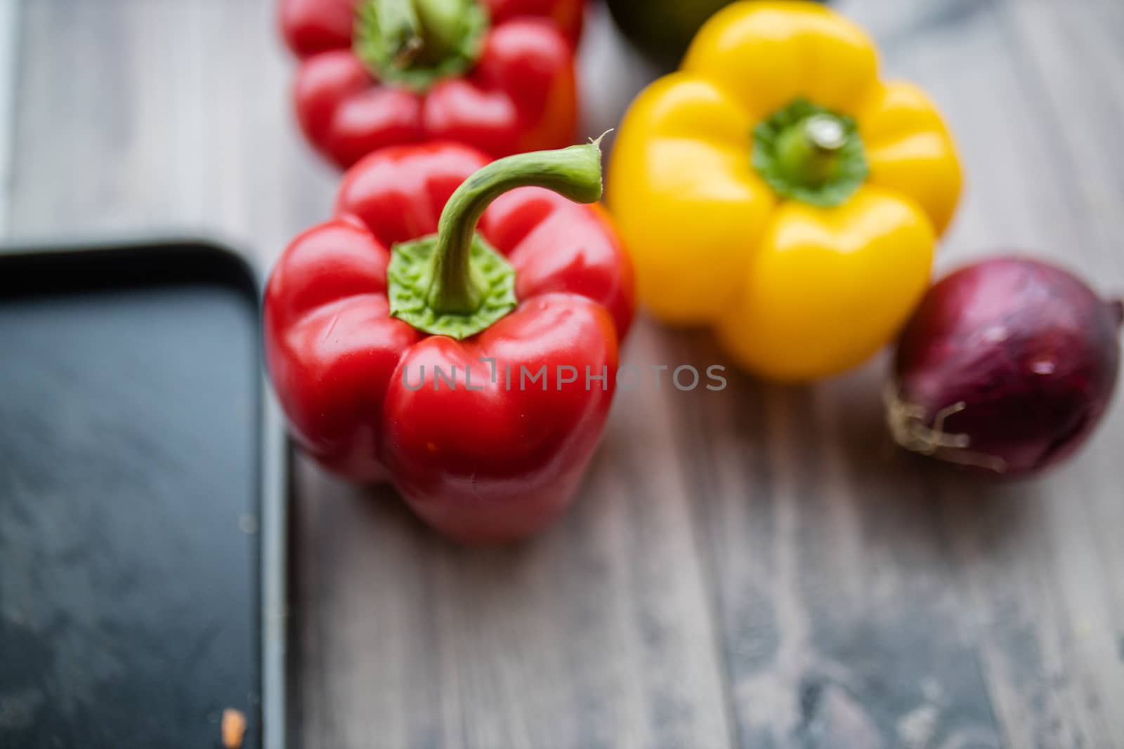 Red and yellow bell peppers up close on a wooden table. Fresh and colorful vegetables on table.Vegan meal ingredients