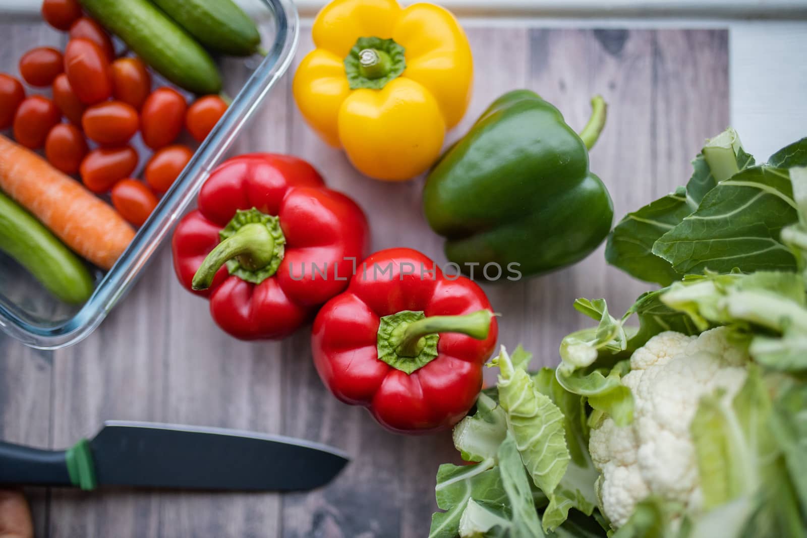 Colorful bell peppers, carrots, tomatoes, zucchini, and cauliflower on table. Fresh vegetables on wooden table from above.Vegan meal ingredients