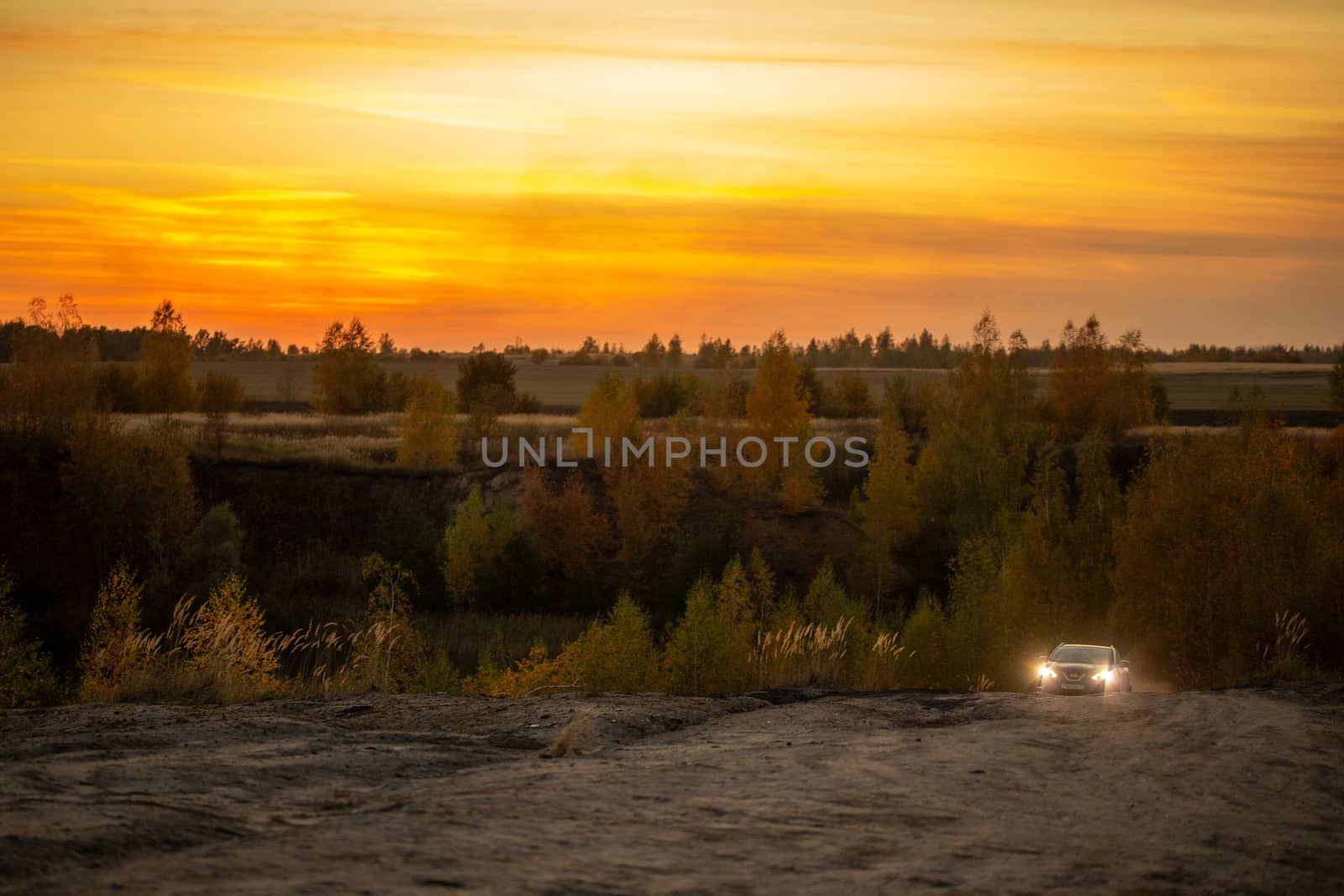 VOLKOVO, RUSSIA - OCTOBER 4, 2020: Blue Nissan Qashqai climbing up on dry dusty dirt road at autumn golden sunset offroad.