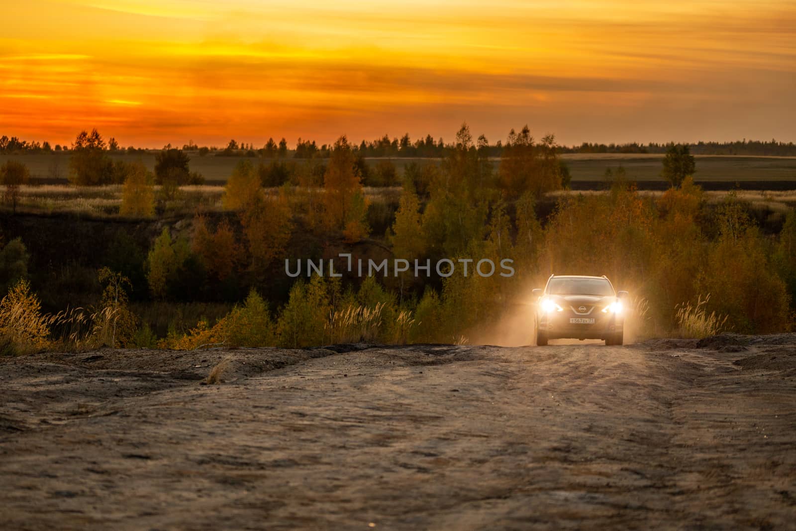 VOLKOVO, RUSSIA - OCTOBER 4, 2020: Blue Nissan Qashqai climbing up on dry dusty dirt road at autumn golden sunset offroad.