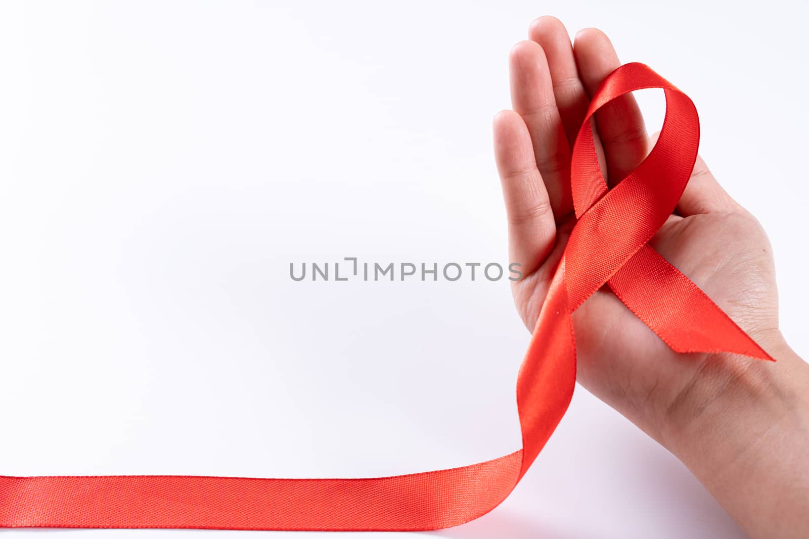 Aids awareness, woman hands holding red ribbon on white background with copy space for text. World Aids Day, Healthcare and medical concept. by mikesaran