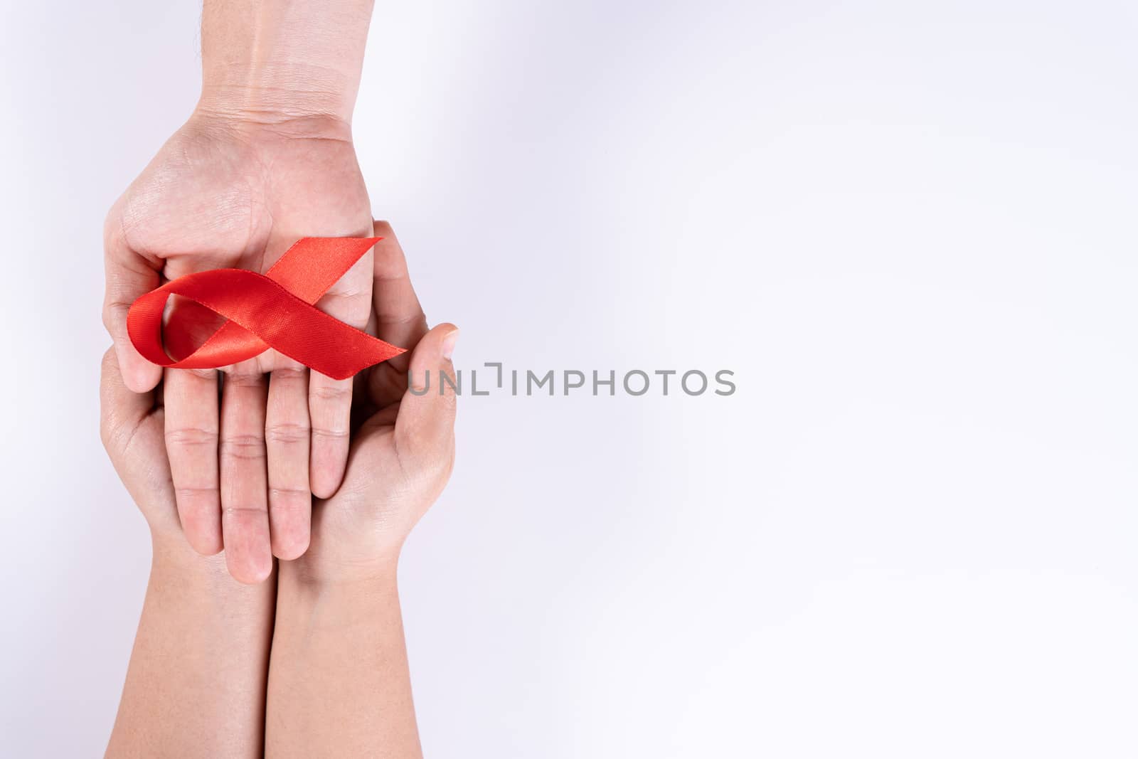 Aids awareness, man and woman hands holding red ribbon on white background with copy space for text. World Aids Day, Healthcare and medical concept. by mikesaran