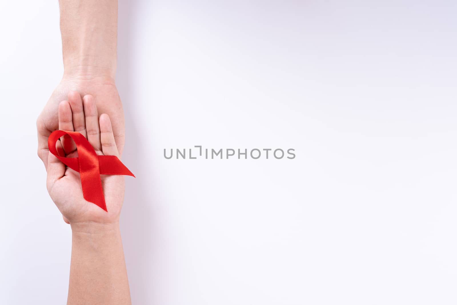 Aids awareness, man and woman hands holding red ribbon on white background with copy space for text. World Aids Day, Healthcare and medical concept. by mikesaran