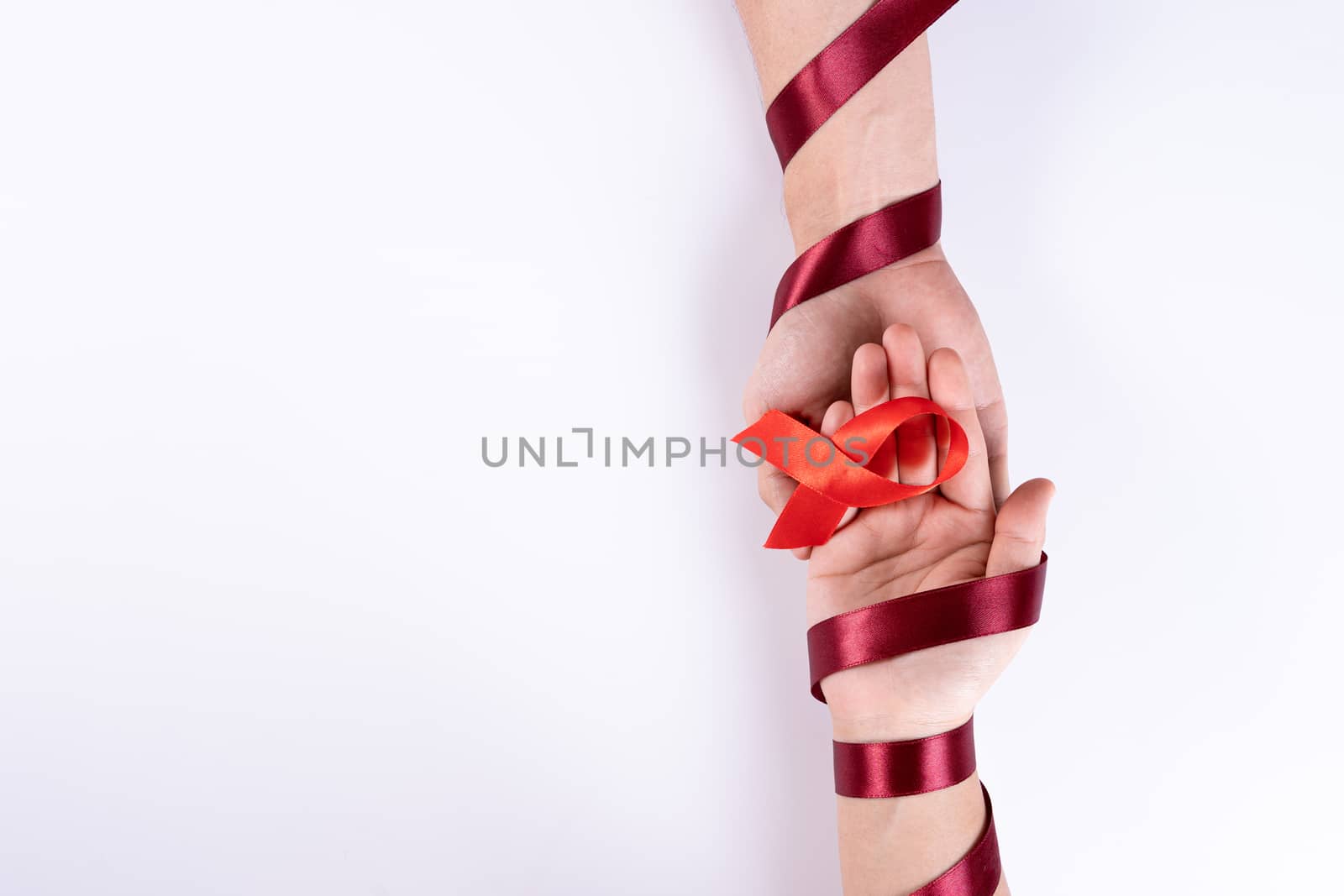 Aids awareness, man and woman hands holding red ribbon on white background with copy space for text. World Aids Day, Healthcare and medical concept.