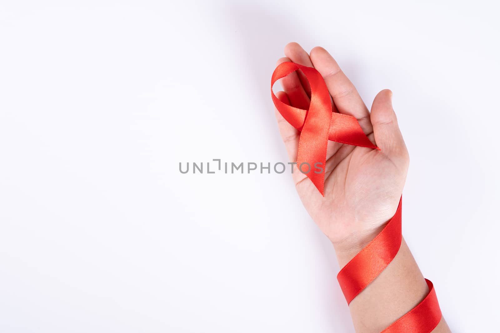 Aids awareness, woman hands holding red ribbon on white background with copy space for text. World Aids Day, Healthcare and medical concept. by mikesaran