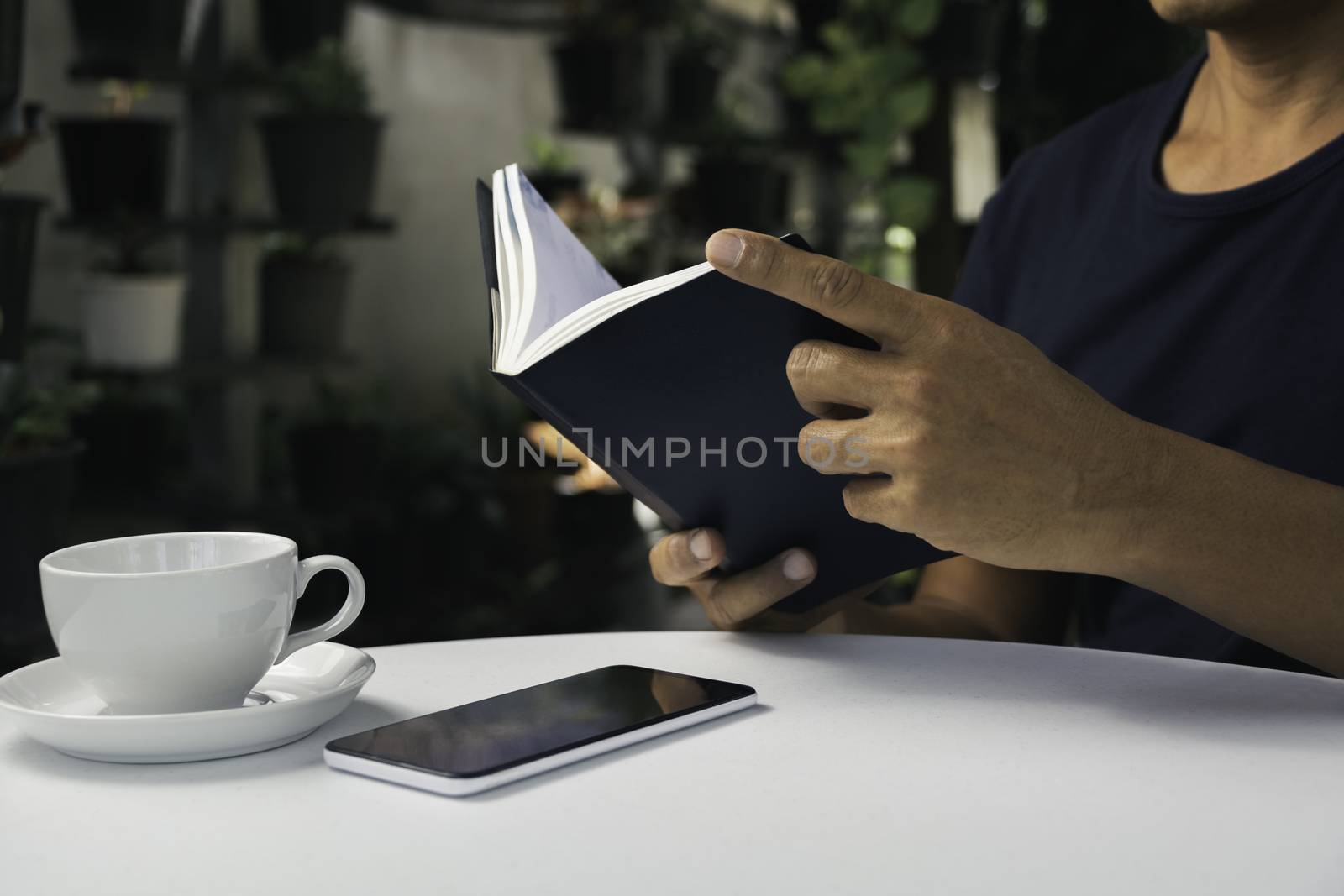 A man reading a book with coffee cup. Man sitting in chair at home, reading book and relaxing.
