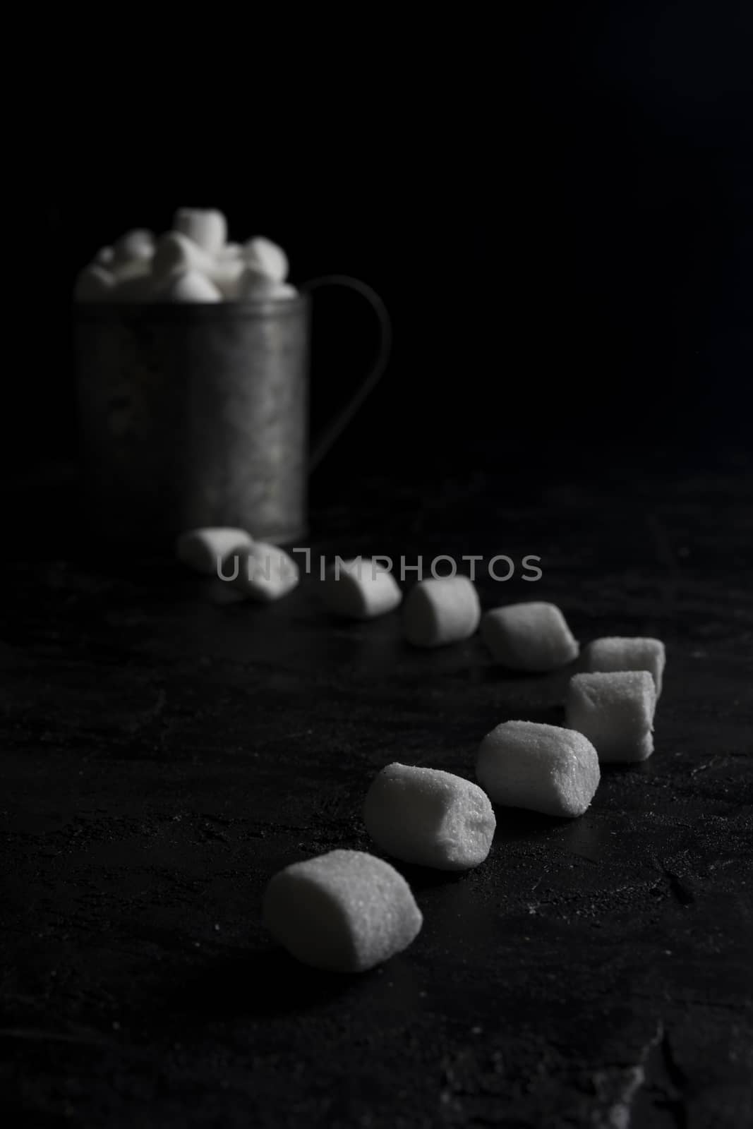 Cup of coffee and marshmallows on black background.