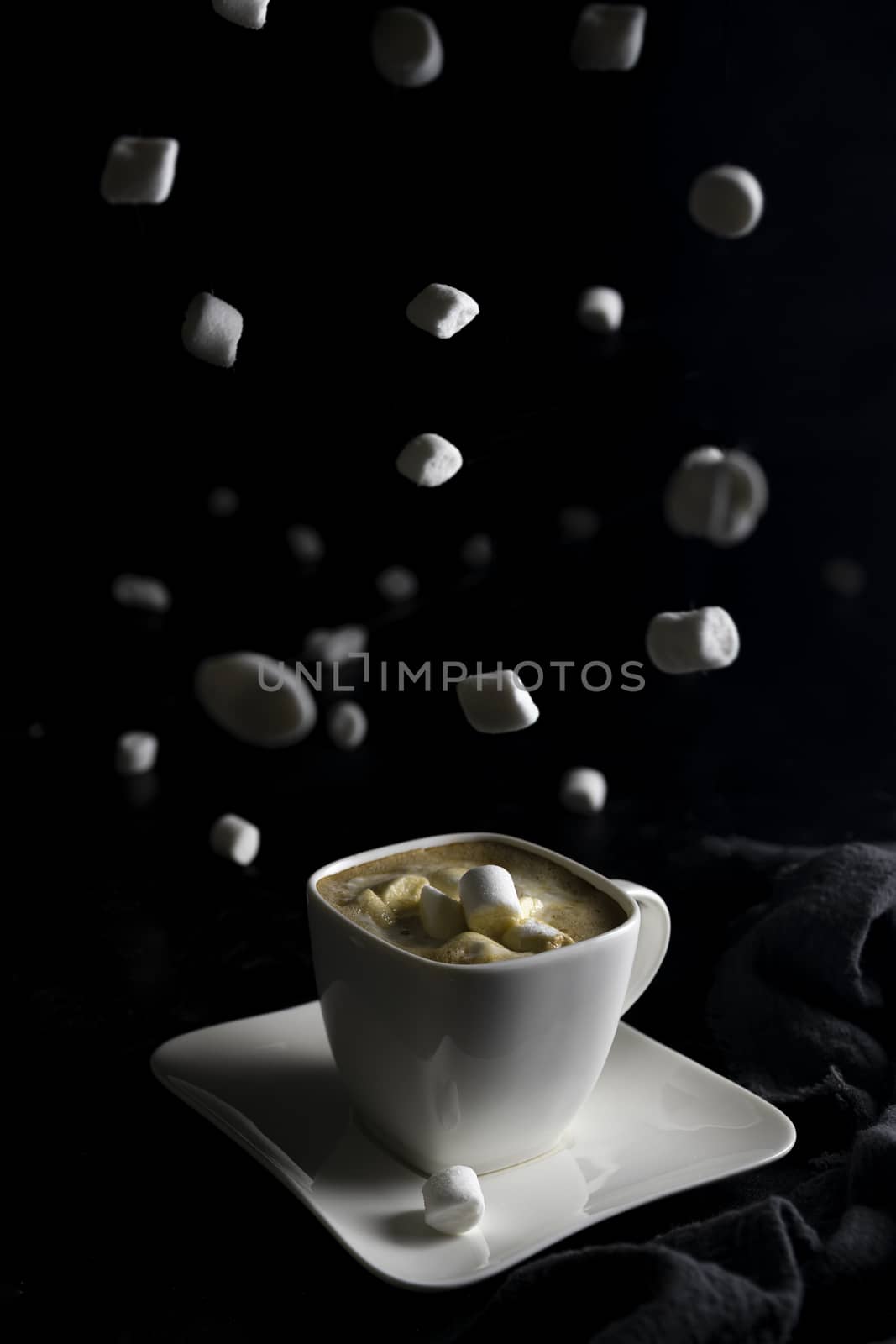 Cup of coffee and marshmallows on black background.