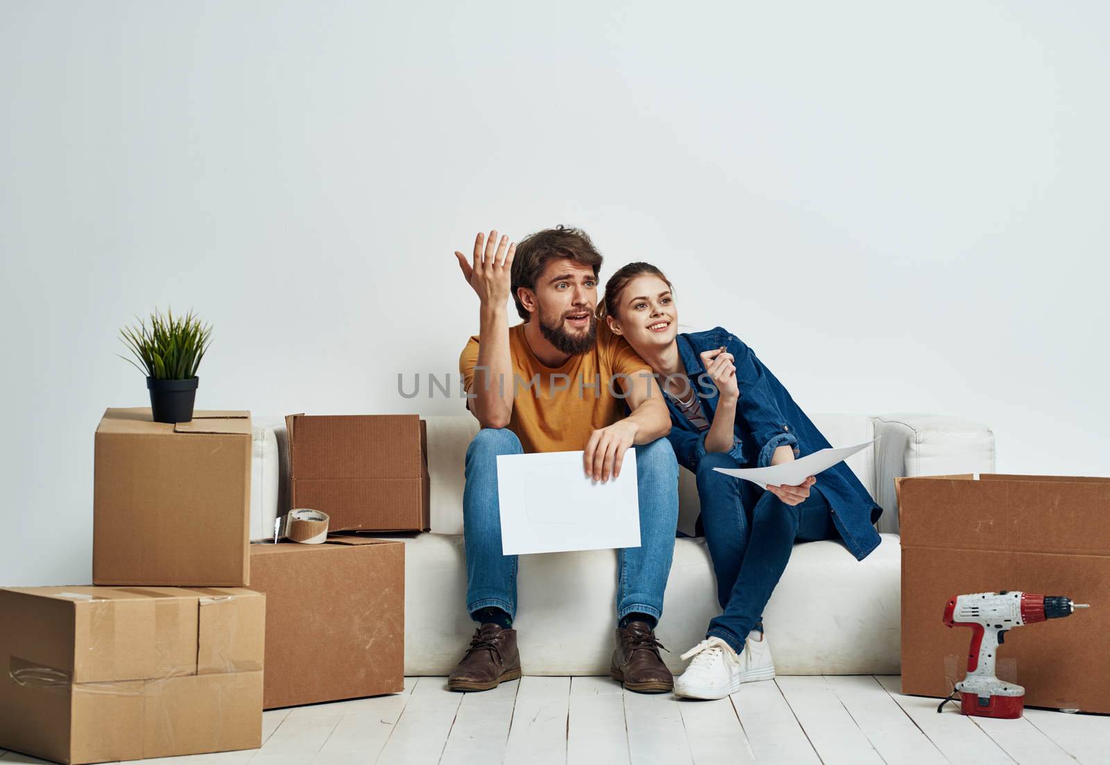 man and woman on white sofa interior cardboard boxes lifestyle. High quality photo
