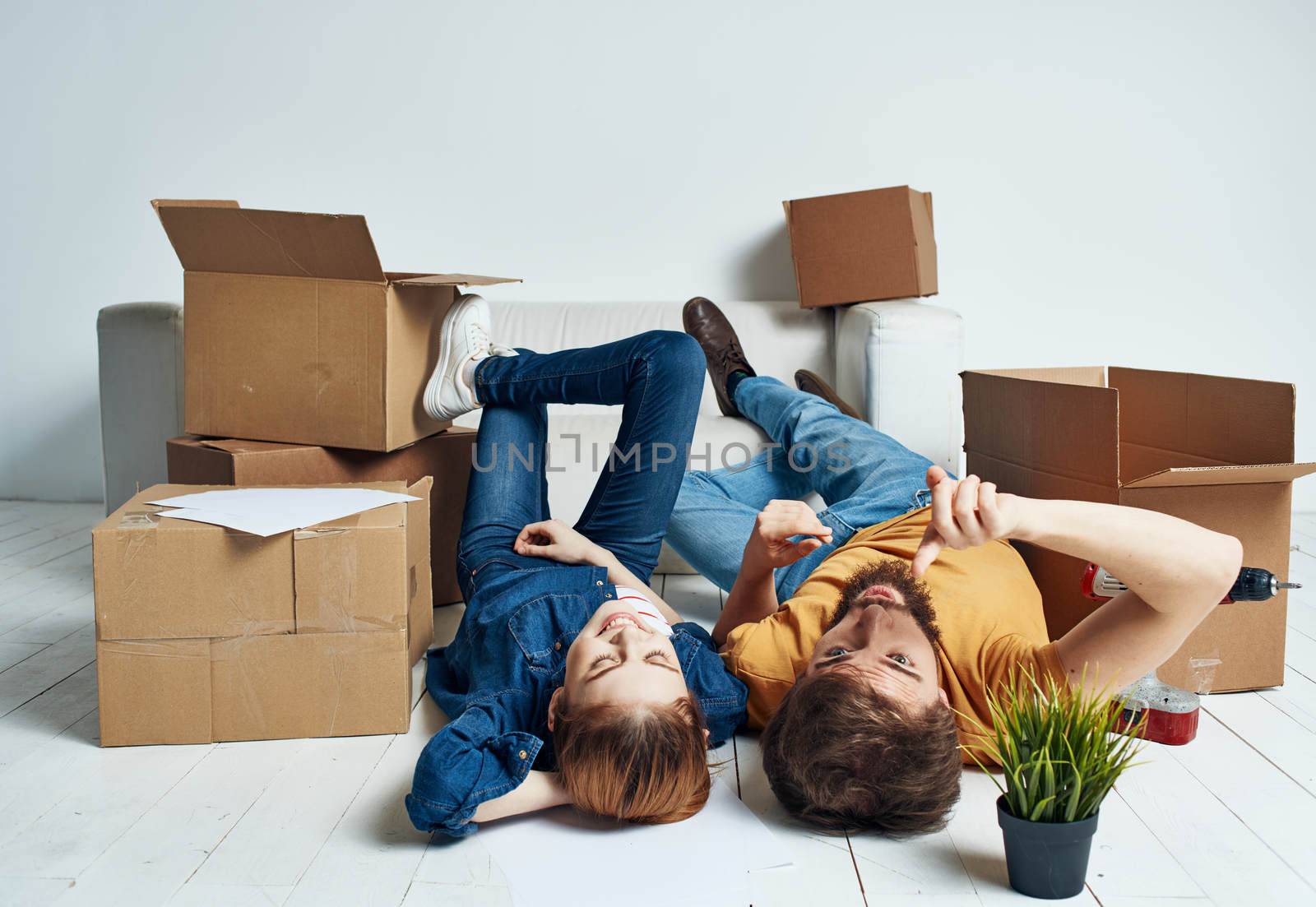 Moving to an apartment a man and a woman lie on the floor and a flower in a pot. High quality photo