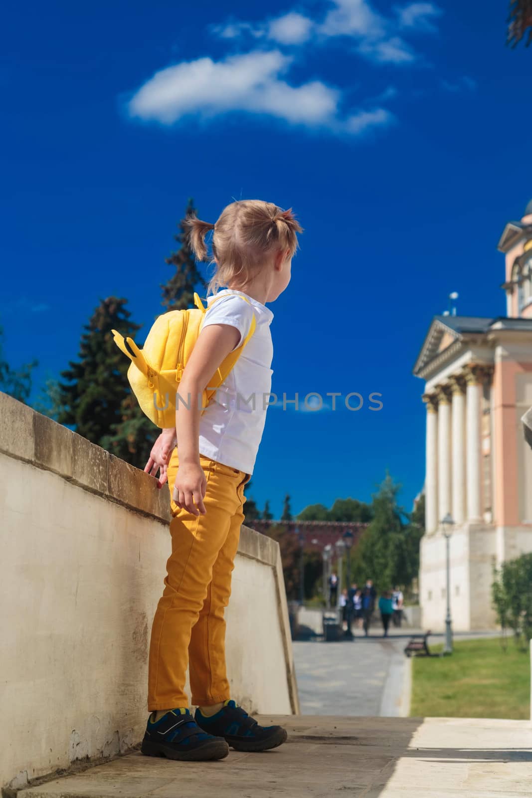 Little girl stands with her back on the porch of the building by galinasharapova