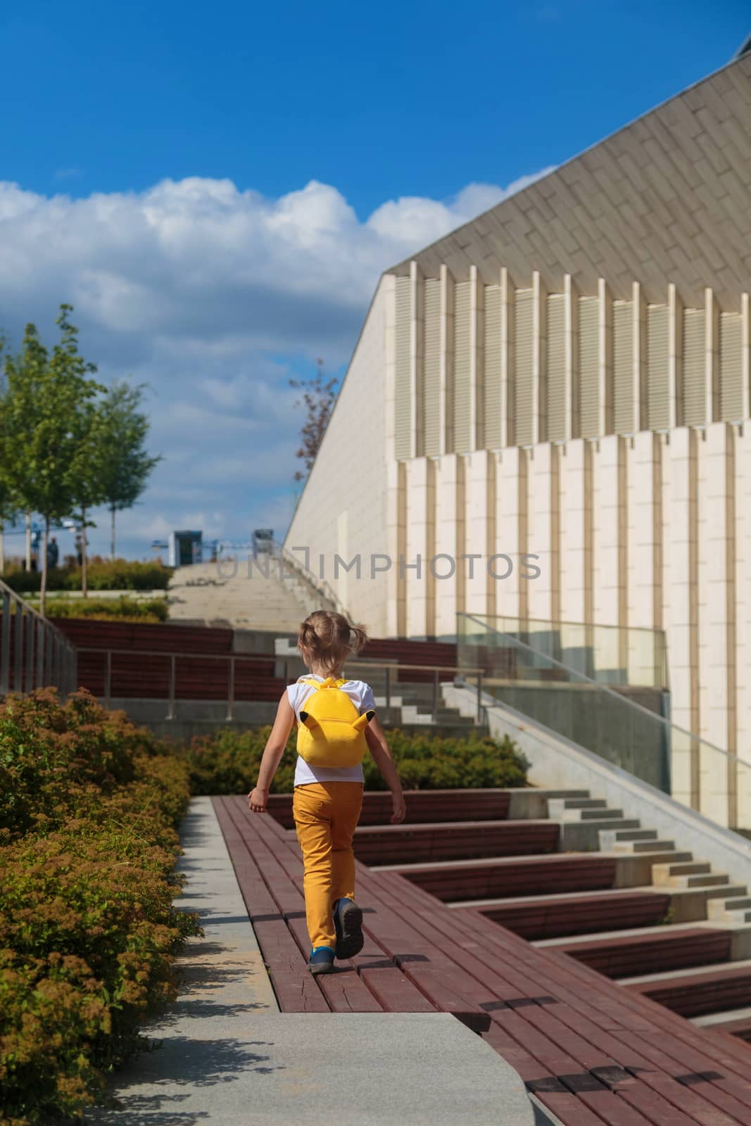 Little Girl in Yellow Jeans Runs Through the Park.