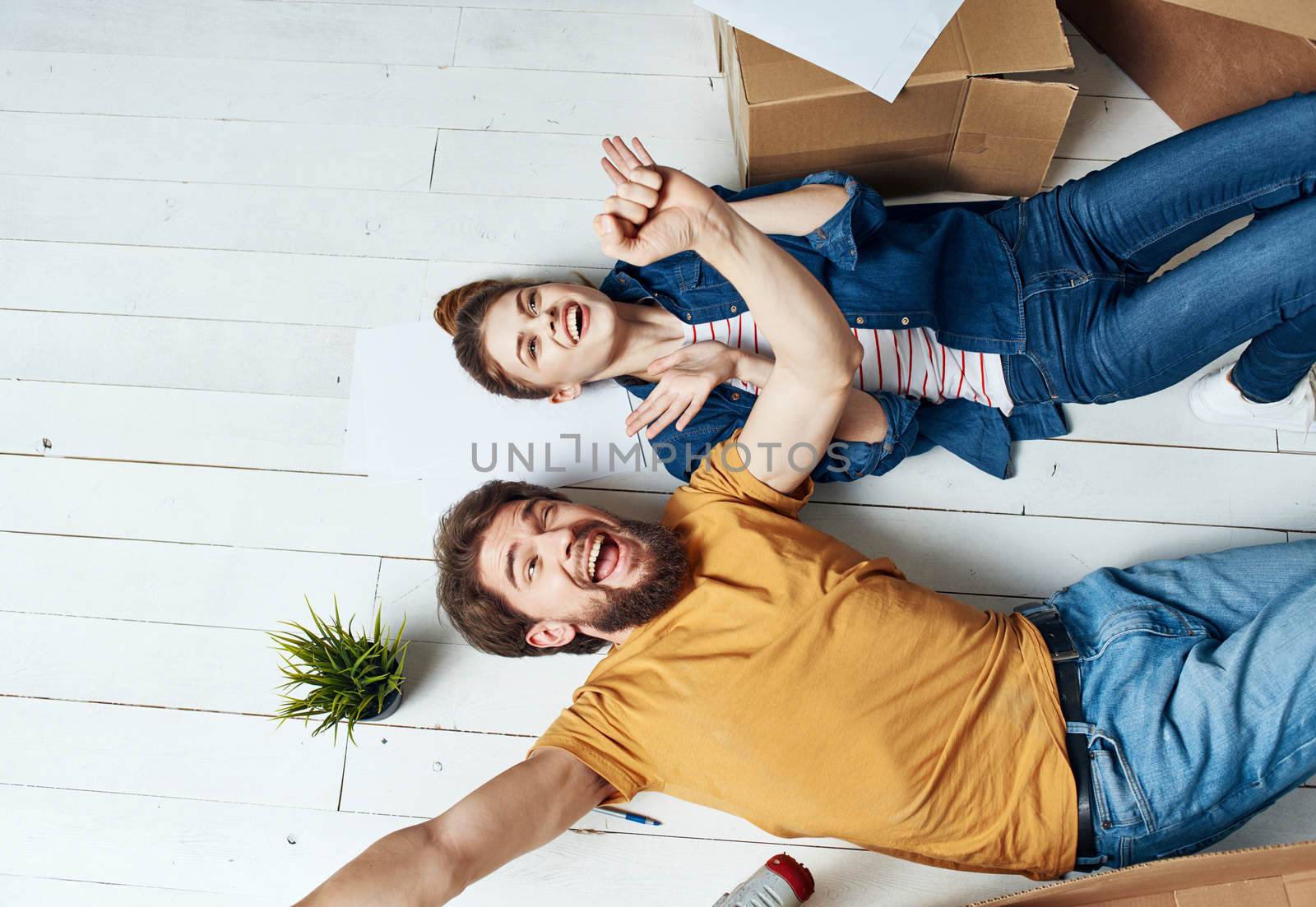 Moving to an apartment a man and a woman lie on the floor and a flower in a pot. High quality photo