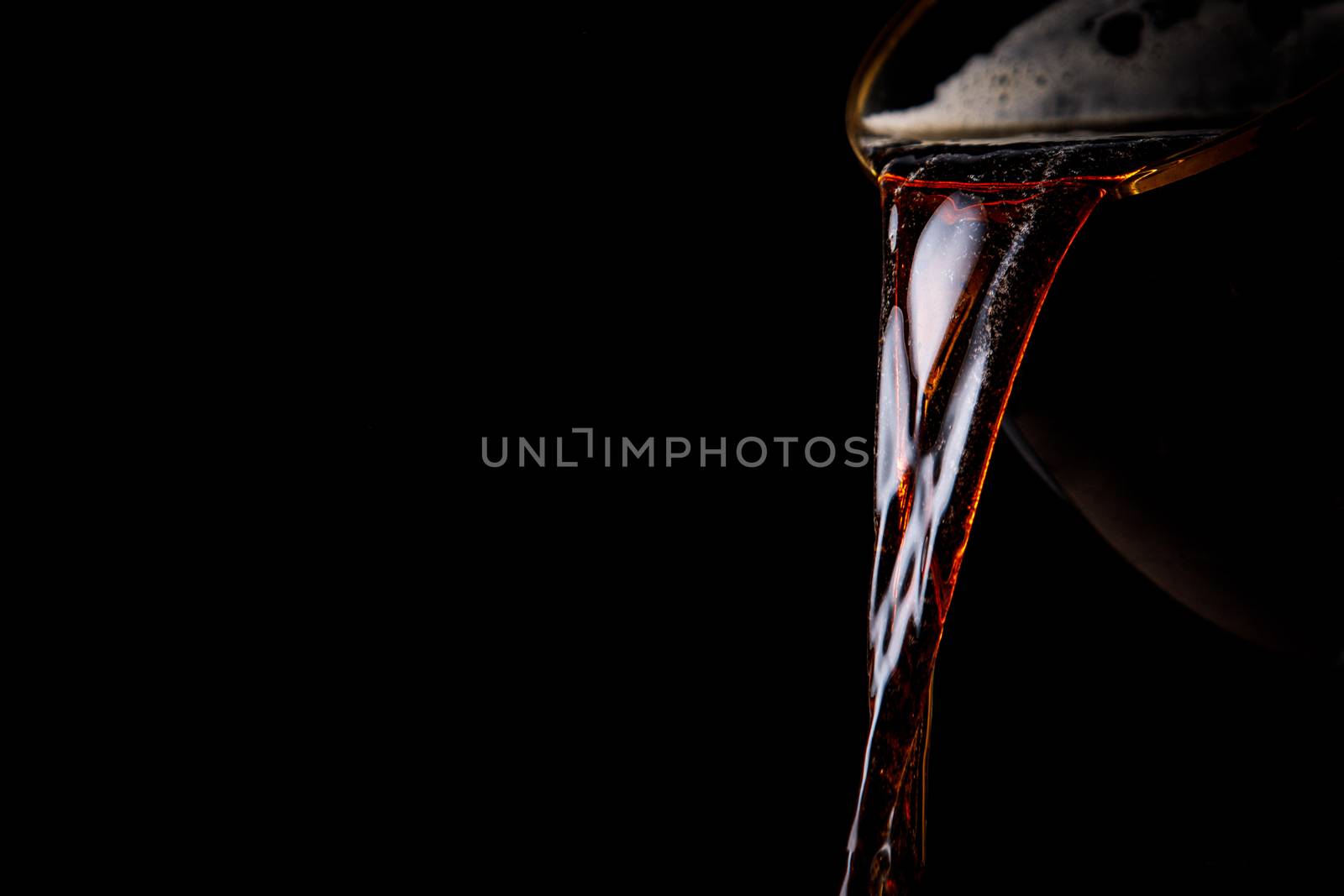 Black beer pouring on a black background