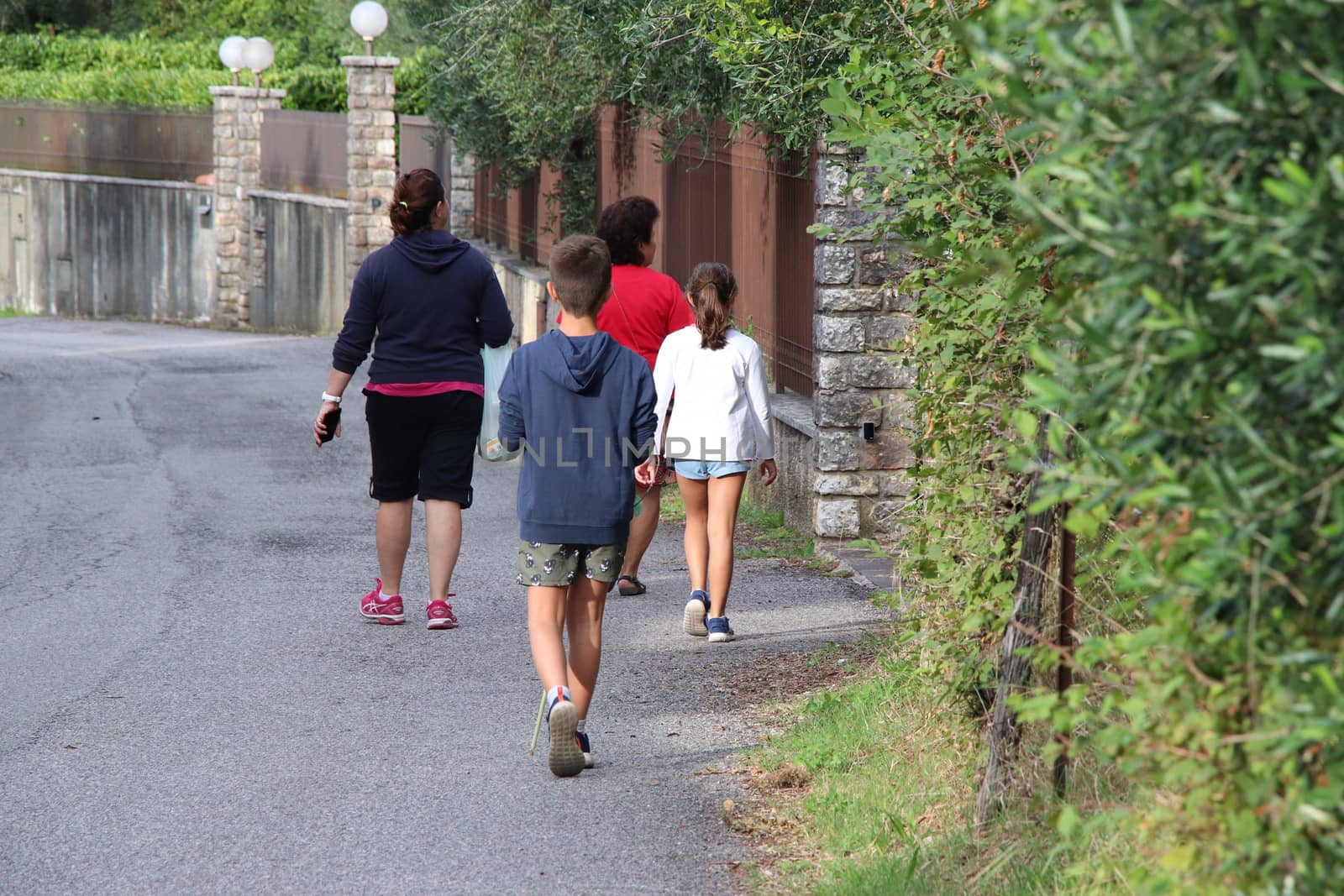 people walking between historic walls, seen from behind