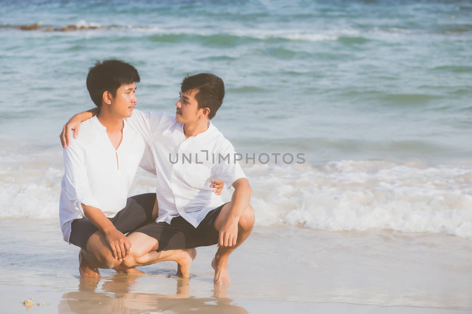 Homosexual portrait young asian couple sitting hug together on beach in summer, asia gay going tourism for leisure and relax with romantic and happiness in vacation at sea, LGBT legal concept.