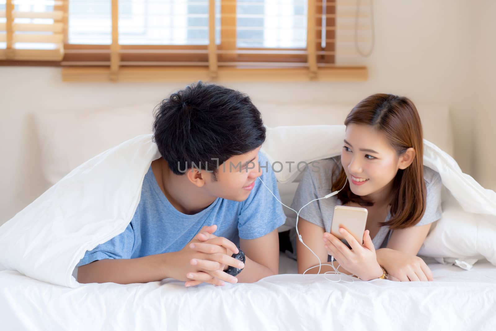 Young asian couple smile listen music with smart mobile phone on by nnudoo