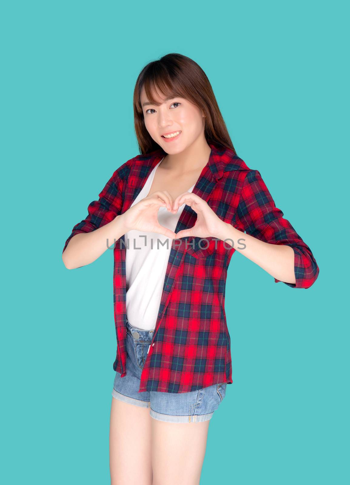 Beautiful happy young asian woman wear travel summer gesture heart shape with hand having confident isolated on blue background, asia teenager girl expression with cheerful and fun while trip.