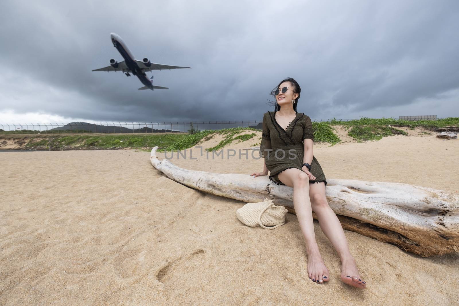 Woman tourist on the beach watching the landing planes at Island by Surasak