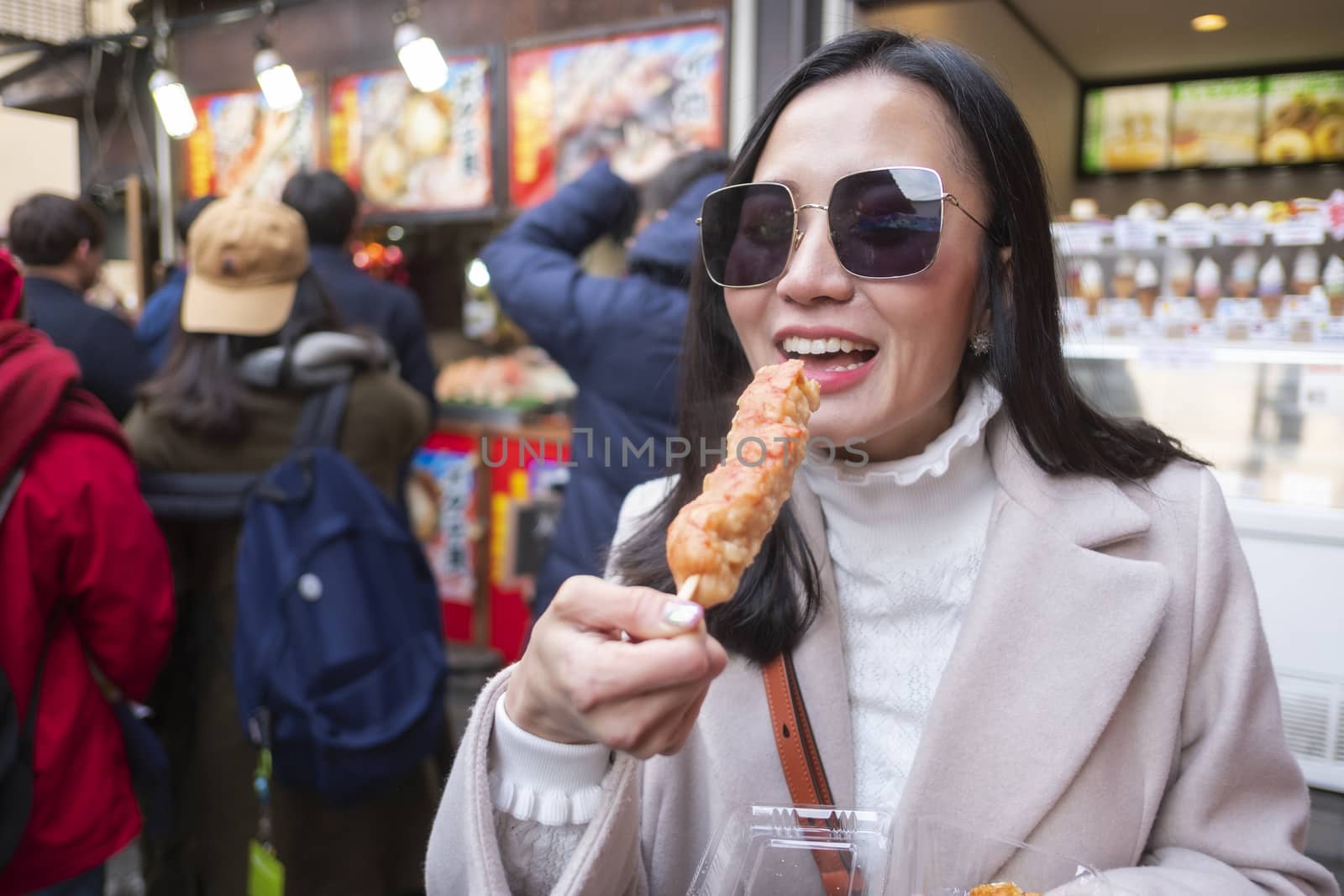 Young tourist woman eating yakitori, chicken grilled as the famo by Surasak
