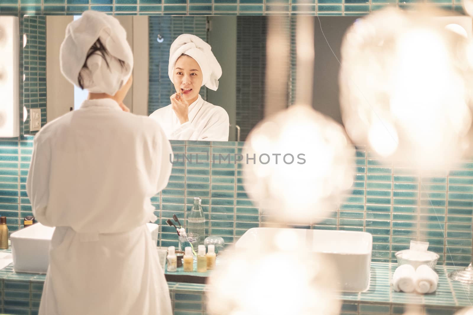 Young woman putting on makeup after shower 