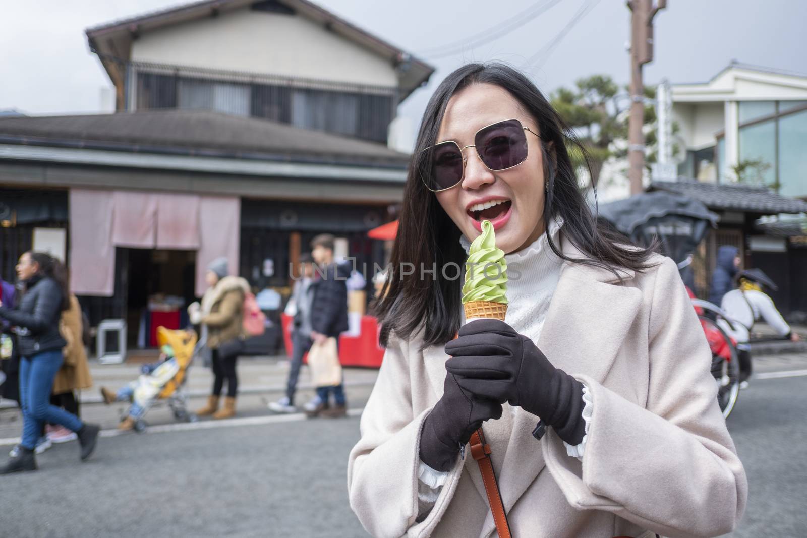 Young tourist woman eating ice cream cone street food at bamboo forest Arashiyama in Japan