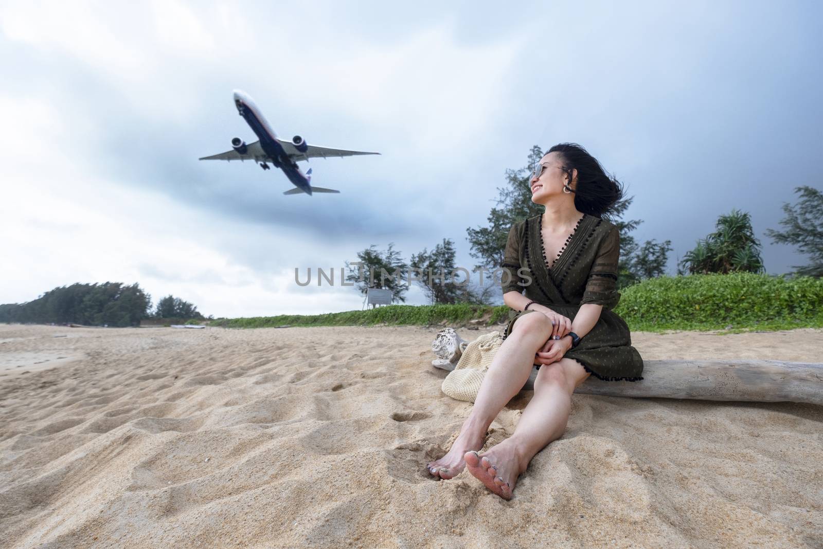 Woman tourist on the beach watching the landing planes at Island Phuket in Thailand. Impressive paradise. Hot beach Mai Khao. Amazing landscape