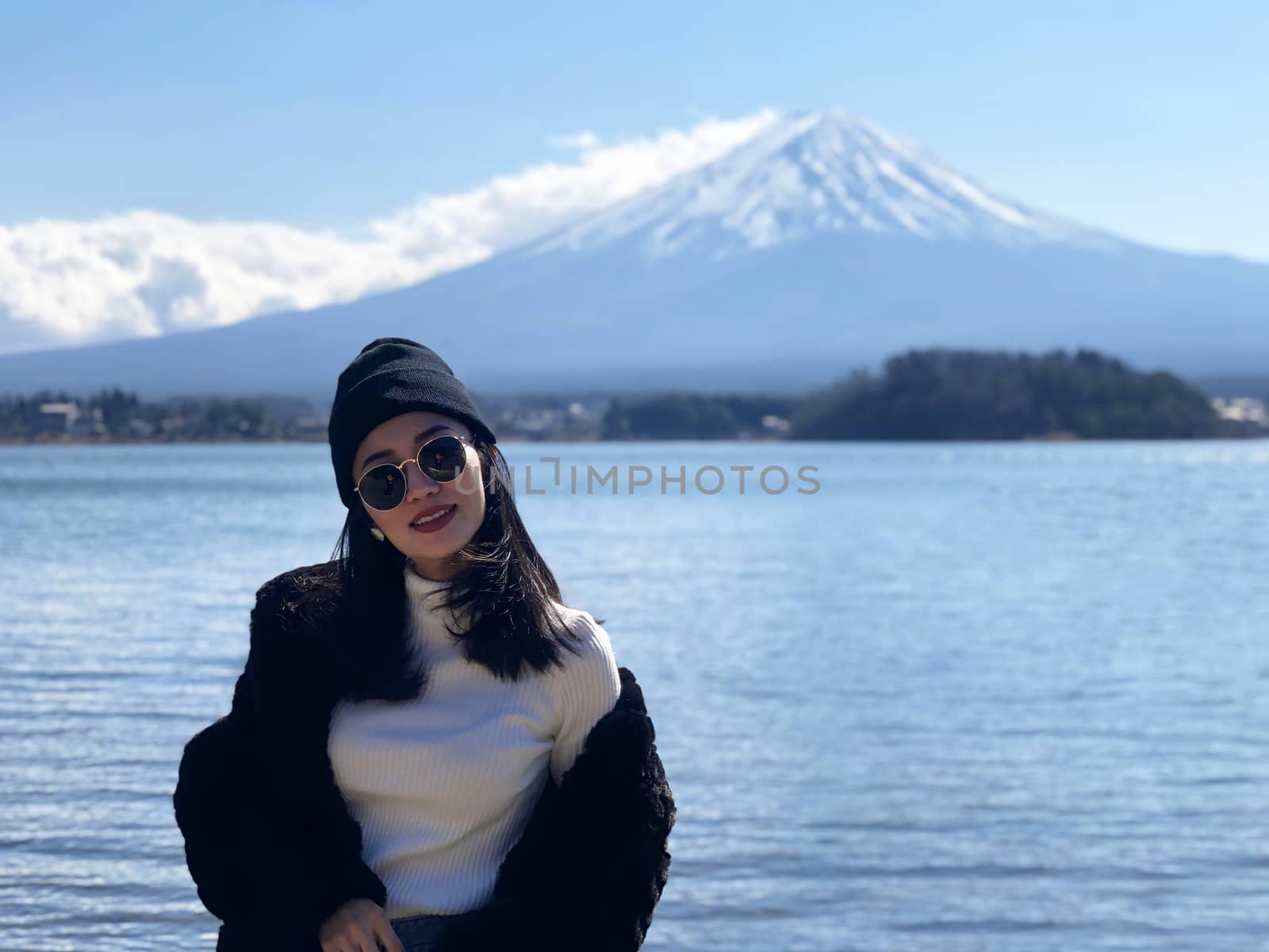 Beautiful smiling woman tourists are traveling and feel happy with Mt Fuji in the morning on the lake kawaguchiko, Japan