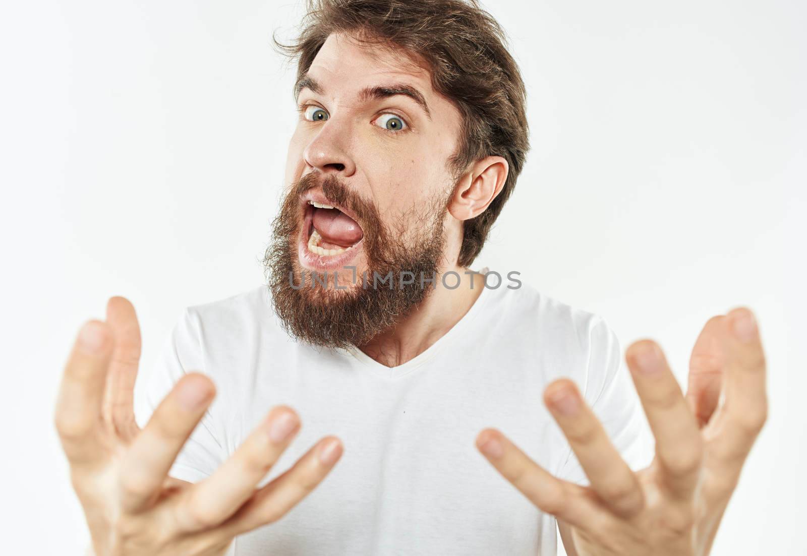 Emotional man on a white background in a T-shirt shows a gesture with his hands. High quality photo