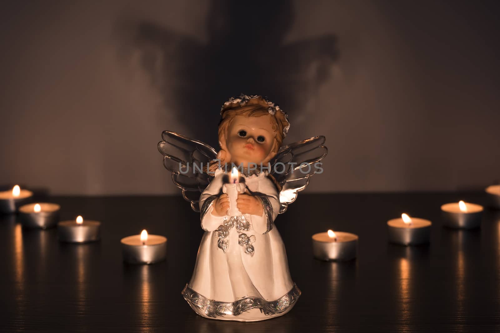 White Christmas angel with lighted candles in the Church. Spiritual deity in religion.