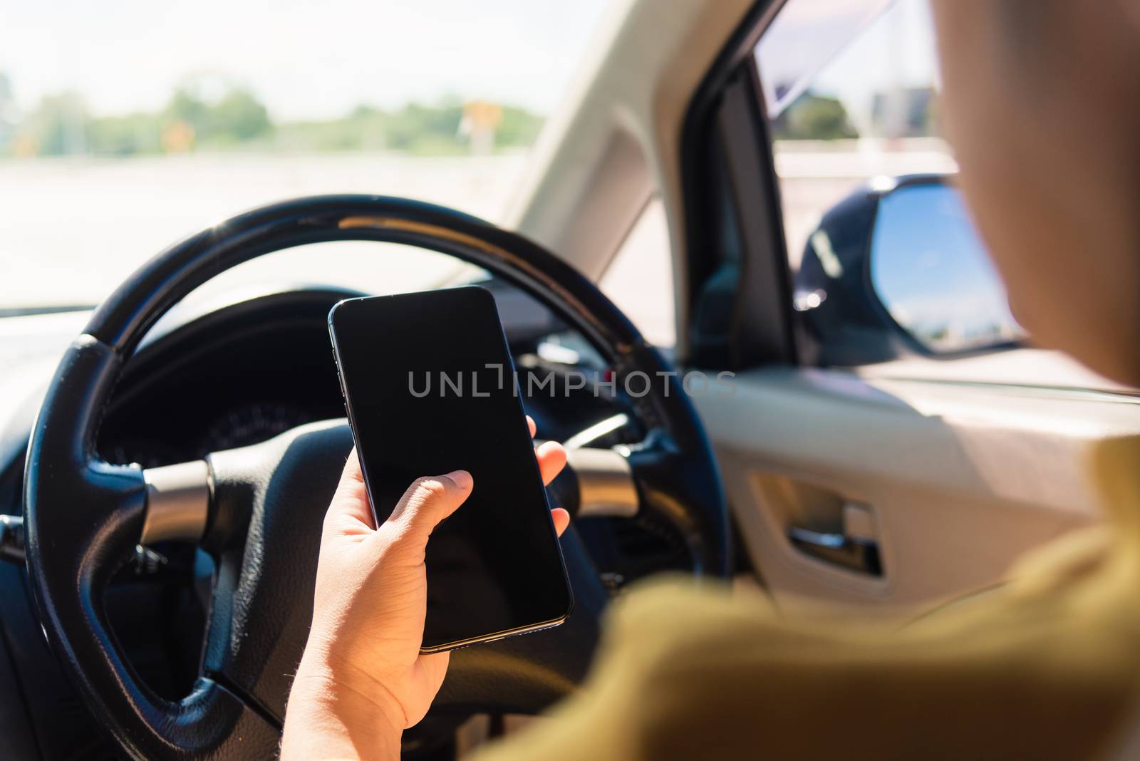 woman inside a car and using a hand holding mobile smartphone by Sorapop