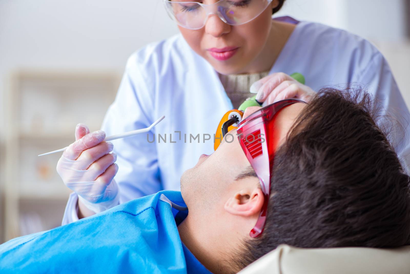 Woman dentist doctor with male patient in hospital by Elnur