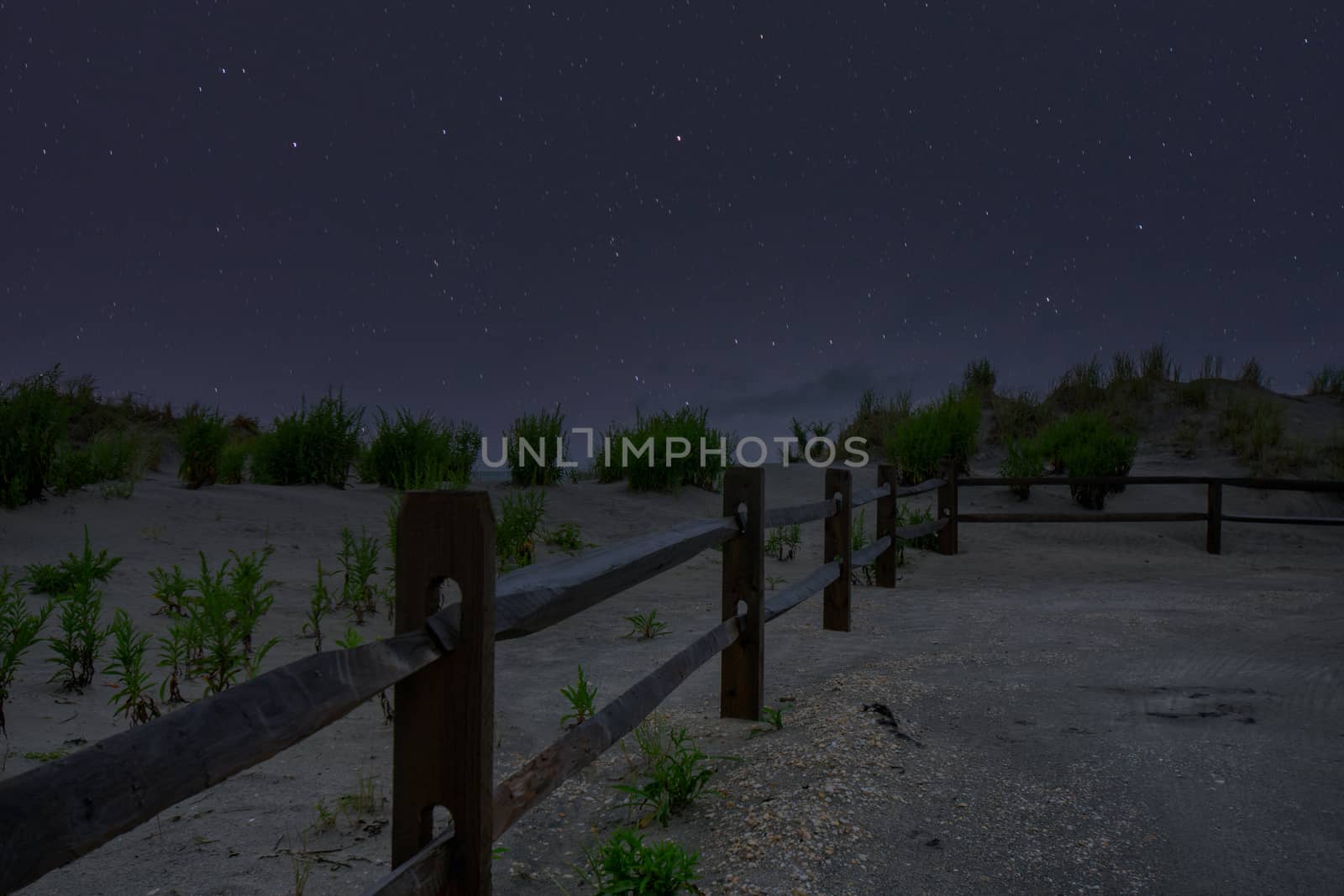 A Beach Path With a Fence on the Side and a Night Sky Full of Stars