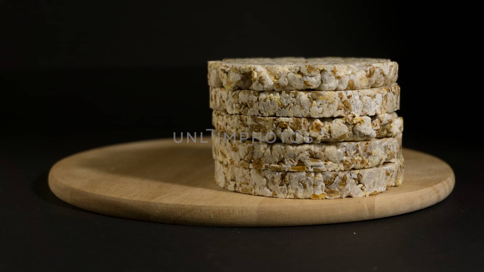 Grain crispbreads crispy rice and diet bread. Stack of puffed whole grain crispbread. Rice cake puffed rice on black background.