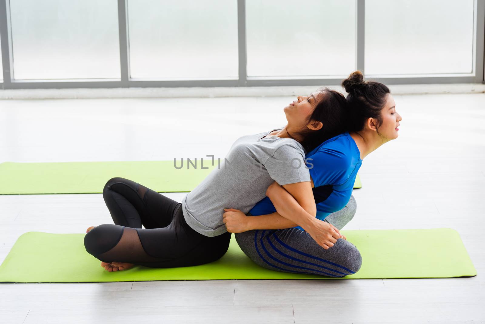 Two Asian women sporty attractive people practicing yoga lesson  by Sorapop