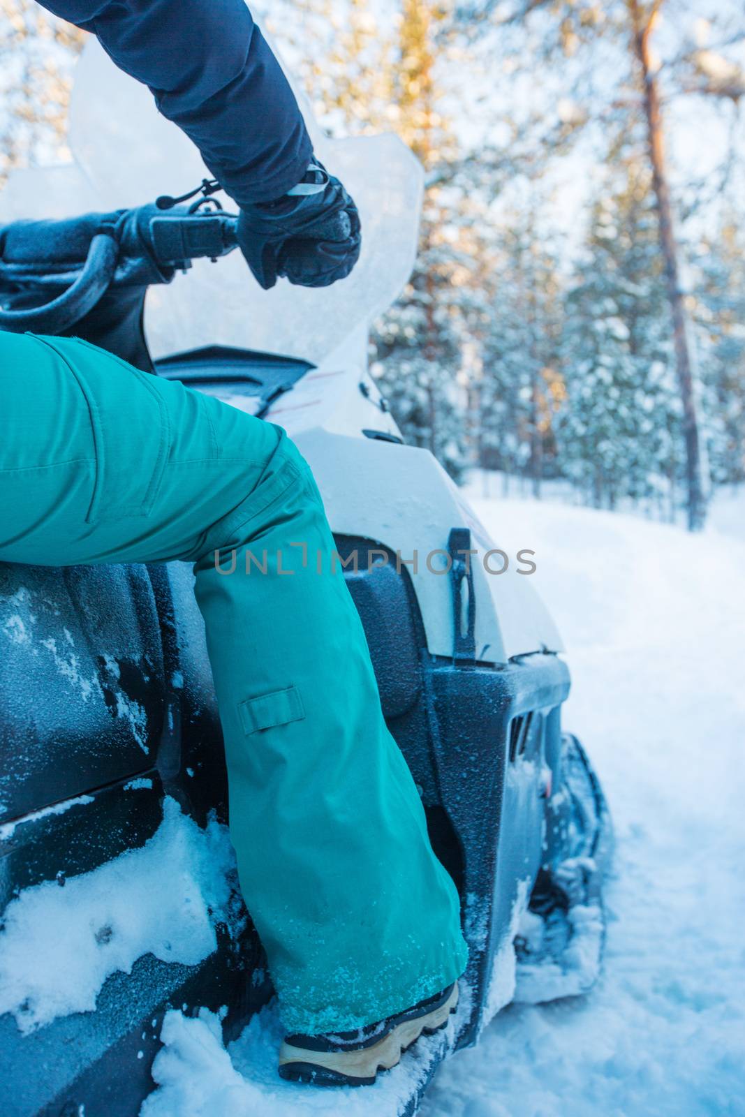 Rider on the snowmobile in winter snow in the morning side view unrecognizible person