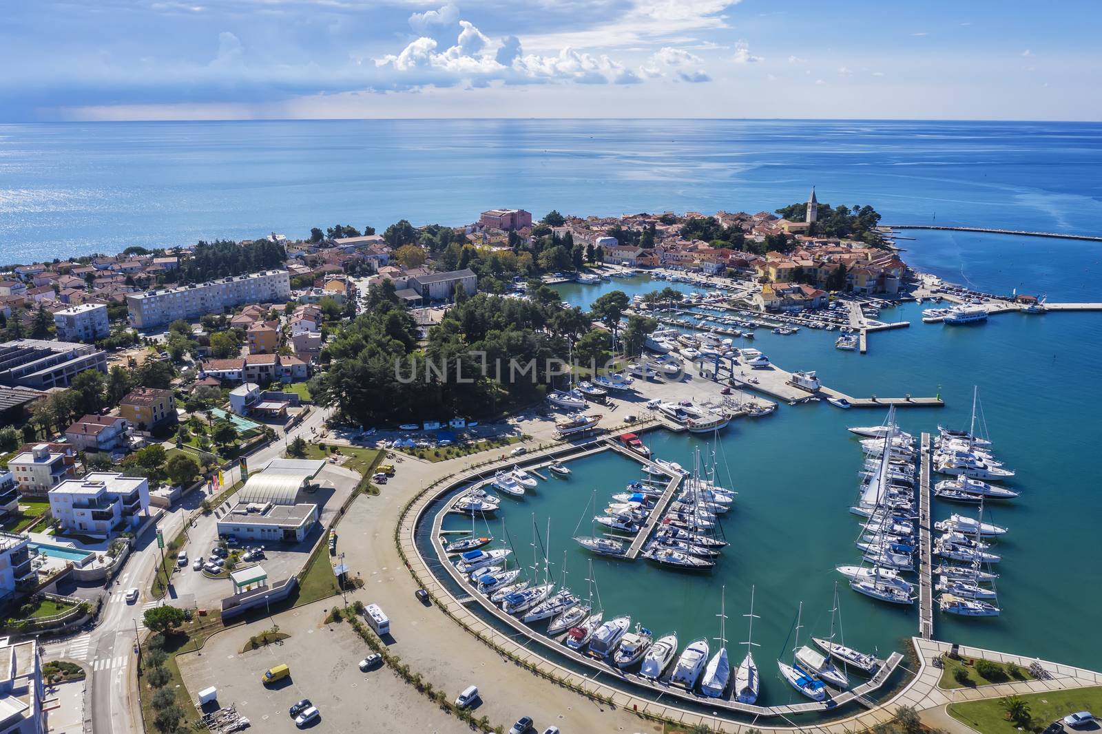 an aerial shot of coastal city Novigrad with boats and yachts in marina, in background old city, Istria, Croatia